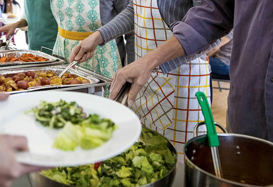 People serving food from a buffet.