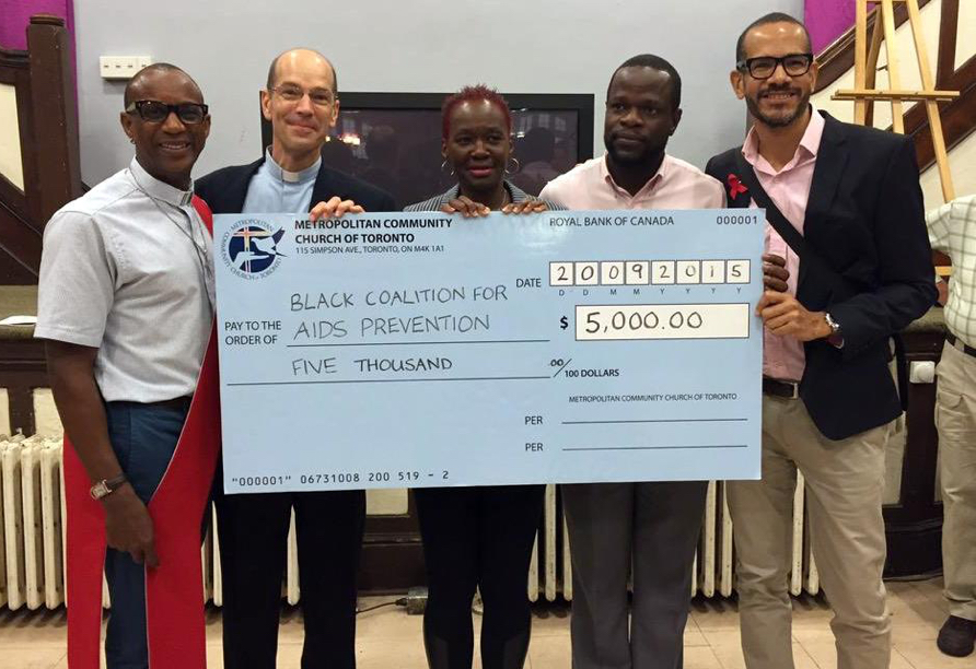 A group of five diverse people holding a large cheque.