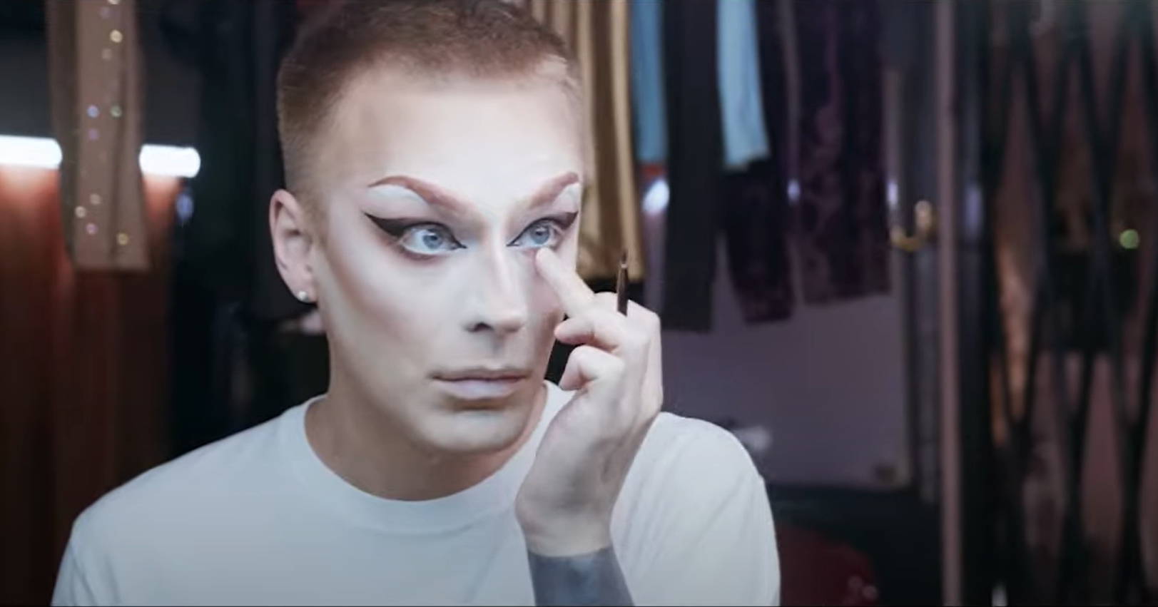 Picture of a person looking into a mirror, fixing their eye makeup.