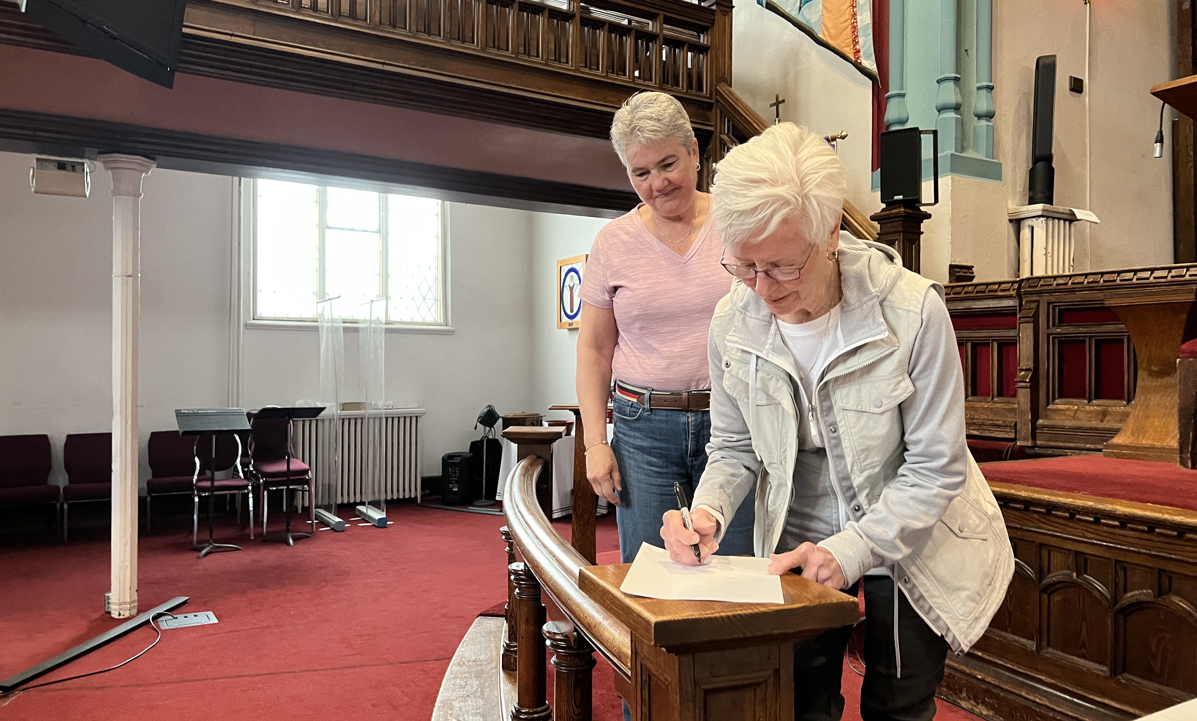 Picture of Lori Boyce, and Jennifer Alexander in the Sanctuary signing a document.