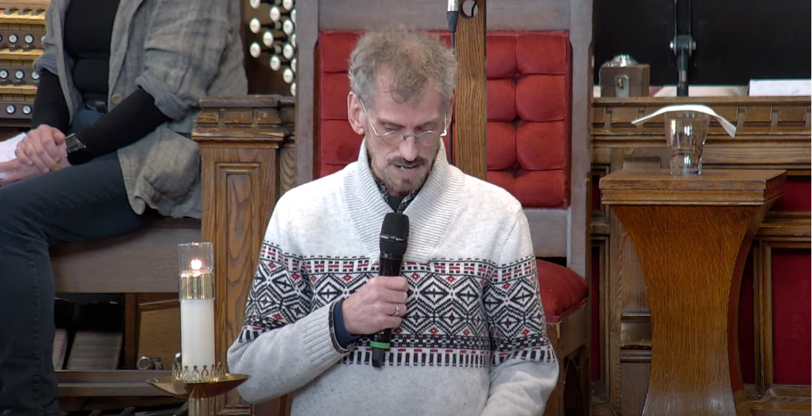 Picture of Mark Asselin delivering the reading at the pulpit.