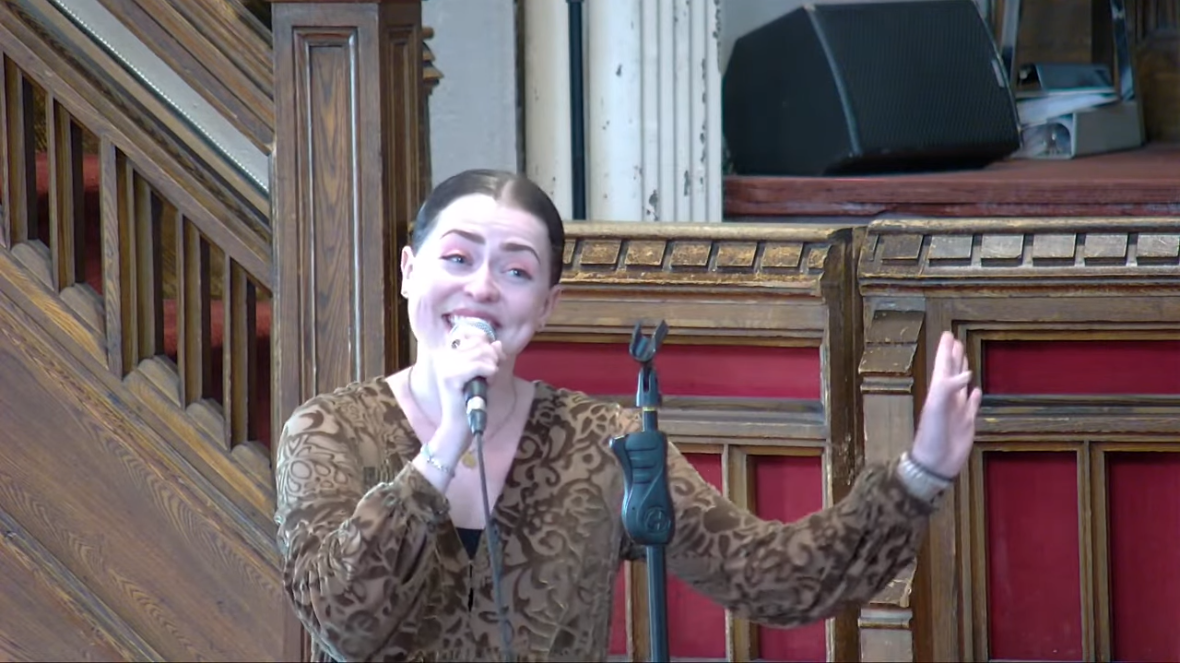 Picture of Arinea Hermans singing with a microphone in hand.