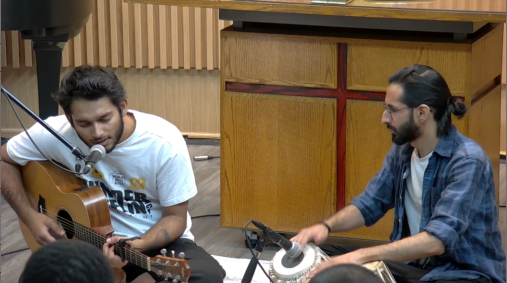 Picture of Just Prince, playing the guitar and Abbas Janmohamed, Playing the tabla in the social hall of MCC Toronto