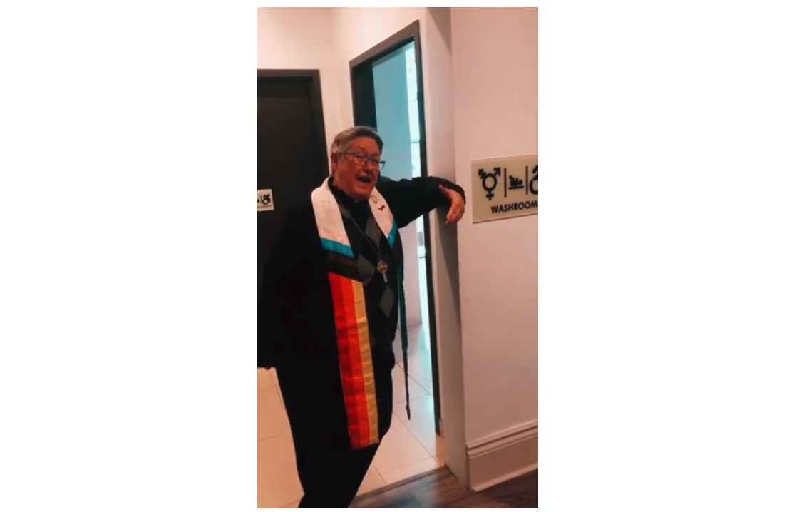 Picture of Rev. Deana standing by the gender-neutral washroom